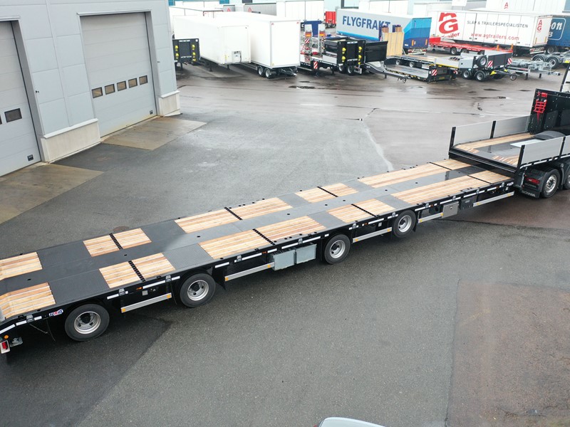 lång jumbotrailer mot våt asfalt kopplad mot bil